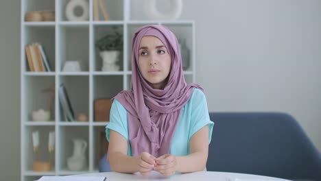 A-woman-in-a-hijab-looks-into-the-camera-and-silently-nods-her-head-and-listens.-Conversation-via-video-link.-Video-conference-listen-to-the-doctor's-recommendations.